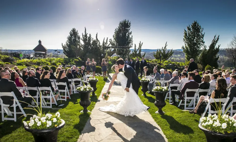 Groom dips bride and kisses her during wedding ceremony.