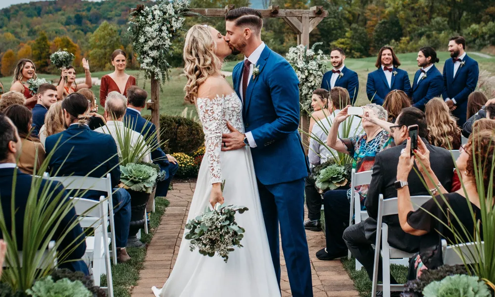 Bride and groom kiss while walking down the aisle at the Ballyowen wedding garden fall ceremony.