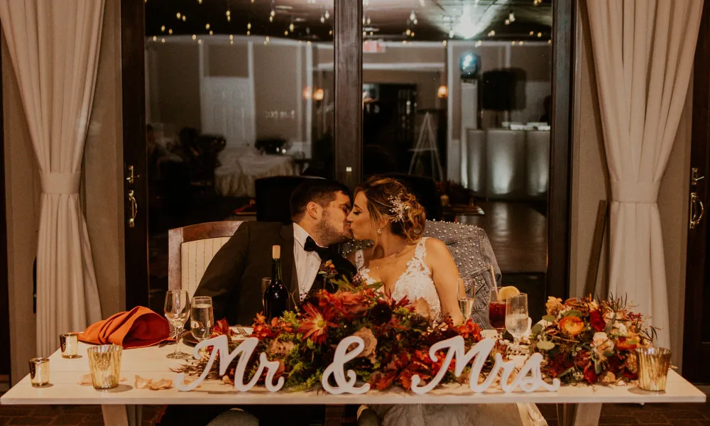 Bride and groom kiss at their sweetheart table during their Bailigh Bluff House Ballyowen wedding reception.