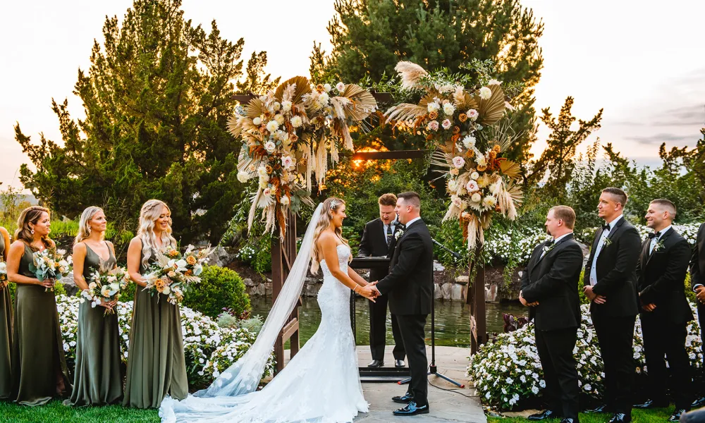 Bride and groom stand hand in hand at Bride walking down the aisle at Wedding Garden ceremony space at Crystal Springs Country Club. 