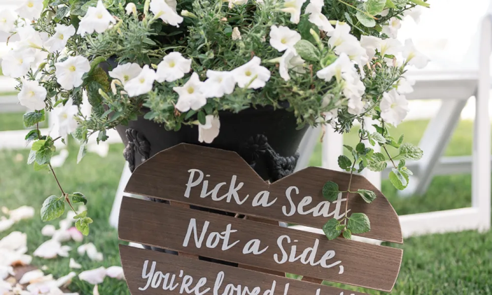 Wooden wedding sign that says pick a seat,not a side you're loved by both the groom and bride during ceremony in Ballyowen Wedding Garden.