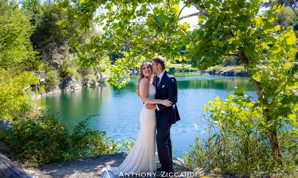 Groom kisses bride in front of Quarry Cliffs. 