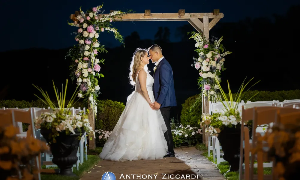 Bride and groom stand under arch in Ballyowen Wedding Garden at nighttime.