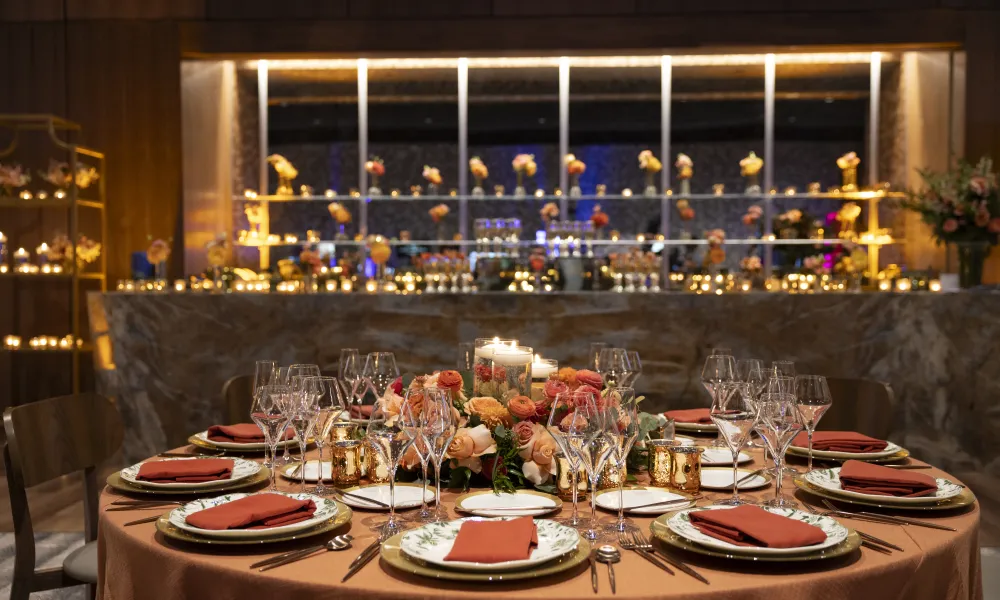 Table set up featuring orange and pink flowers in the Canyon Ballroom for wedding reception.