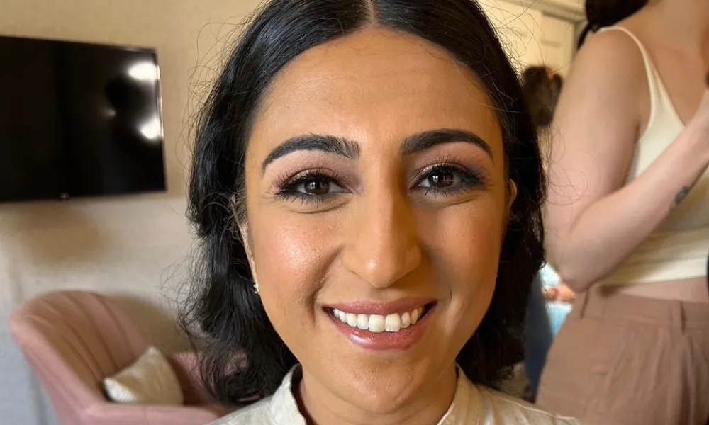 Woman, wearing white shirt, smiles at camera. 