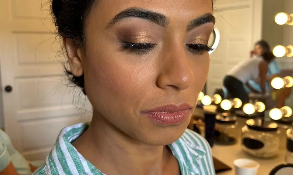 Woman closes her eyes to show off golden eyeshadow. 