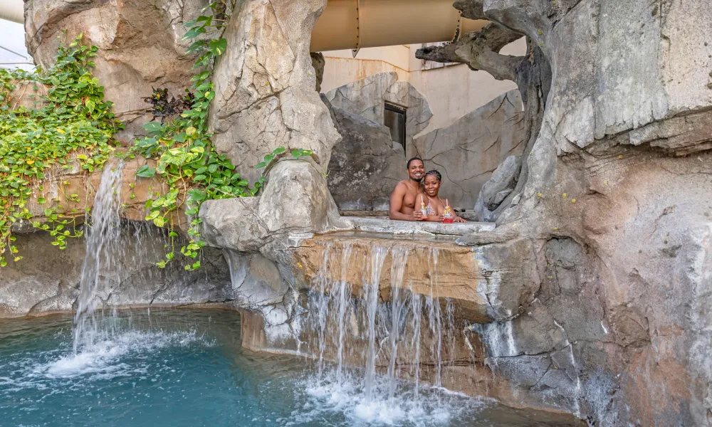 Couple drinking tequila beverages in the Grand Cascades Lodge hot tub. 