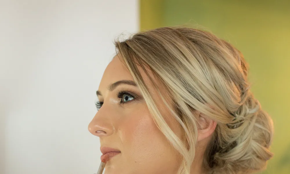 Woman, with updo hairstyle, gets her makeup done. 