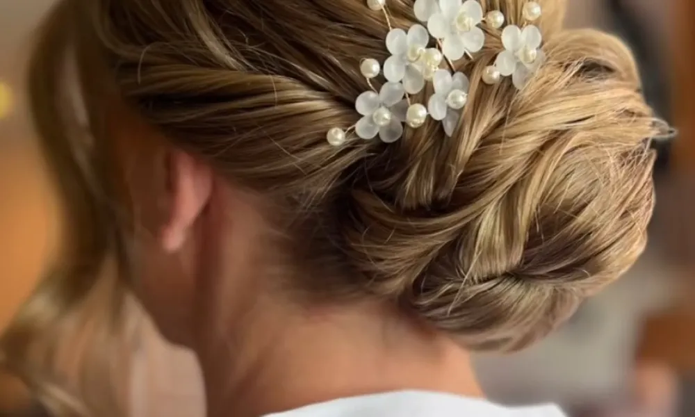 Up do hairstyle featuring gold flower. 