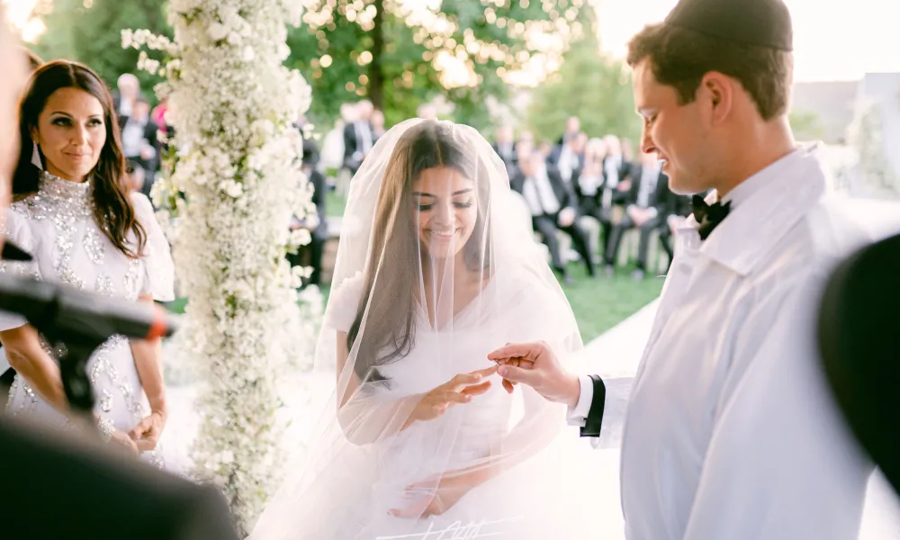 Groom putting ring on bride's finger during their amphitheatre ceremony.