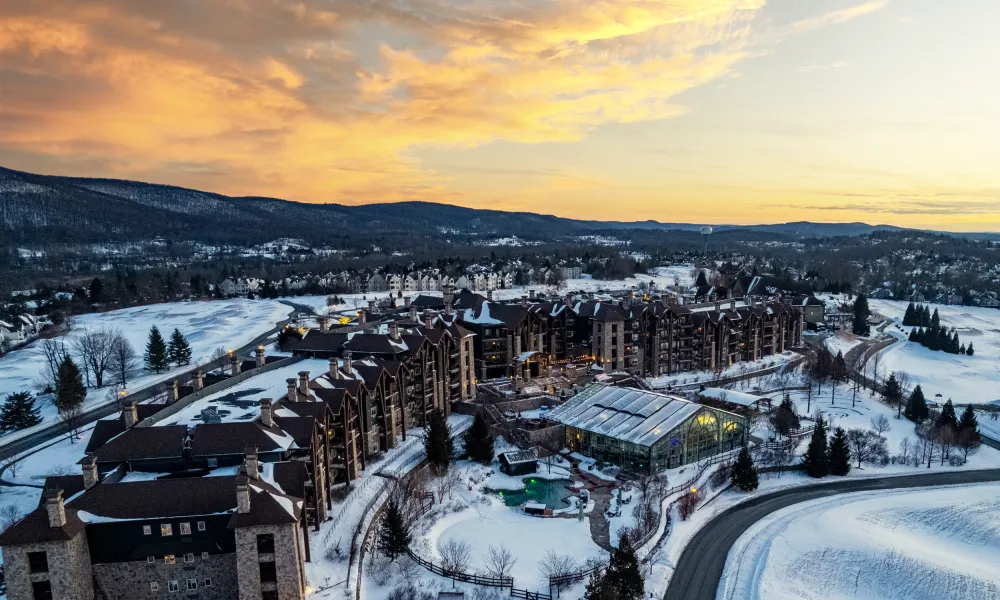 Drone shot of Grand Cascades Lodge showing snow and sunset. 