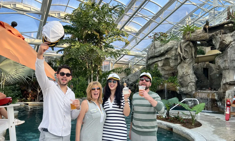 Four people stand with captain hats in Biosphere pool.