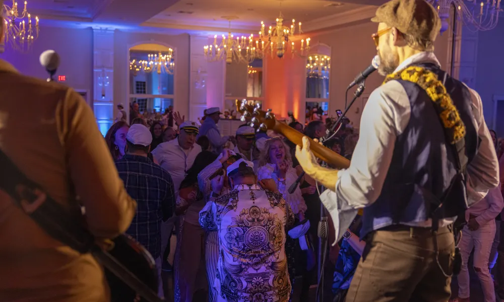 Man performing on stage in front of dancing crowd at Yacht Rock.