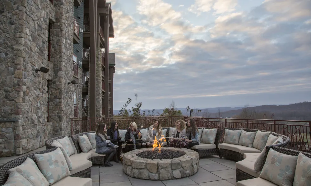 Six girlfriends sitting around firepit.