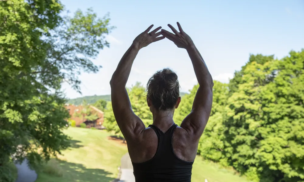 Woman with her arms up above her head facing away.