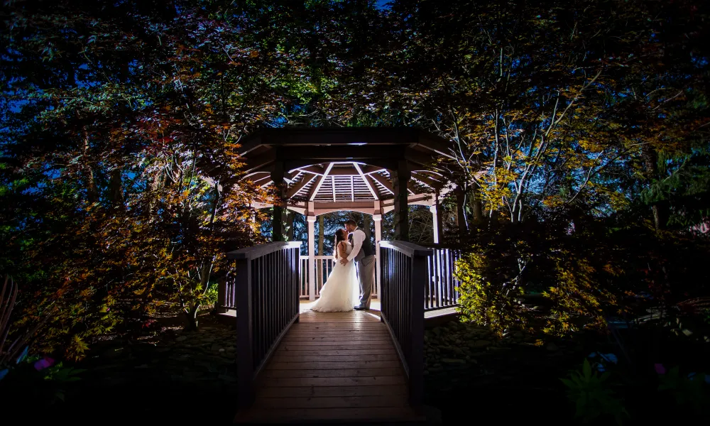 Wedding couple in lit up gazebo at night