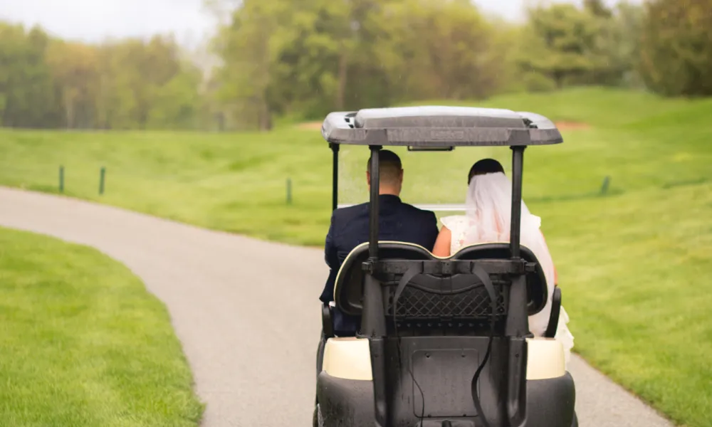 Bride and groom riding away in golf cart