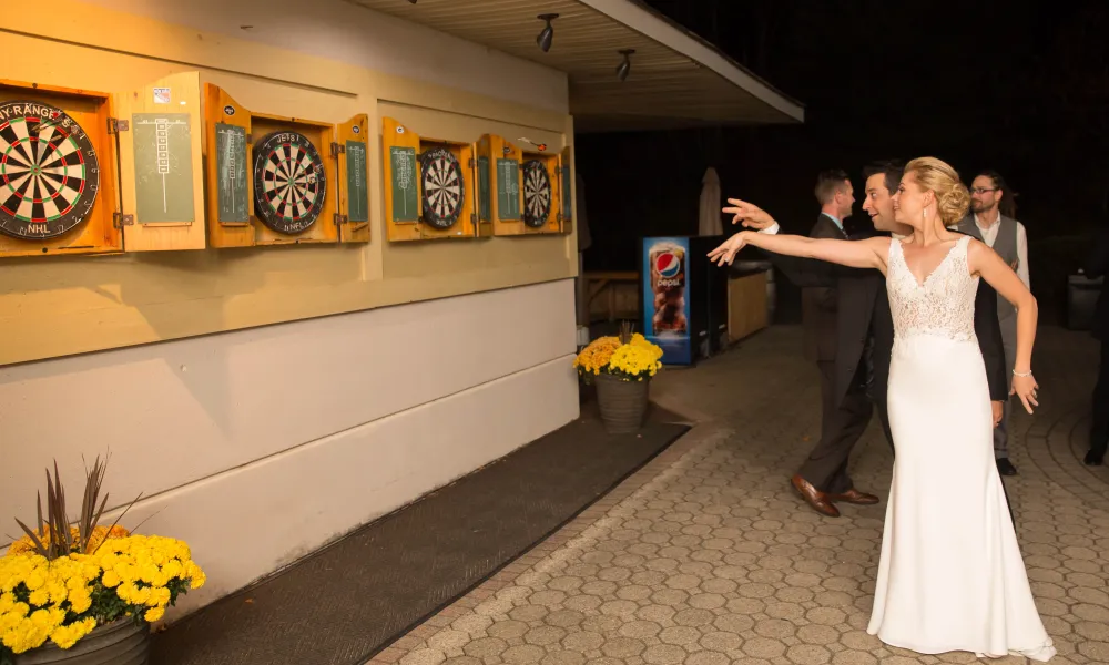 Bride playing darts at wedding reception