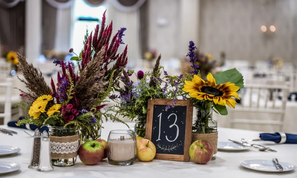 Centerpieces of wedding reception featuring apples, yellow flowers and table number 13. 