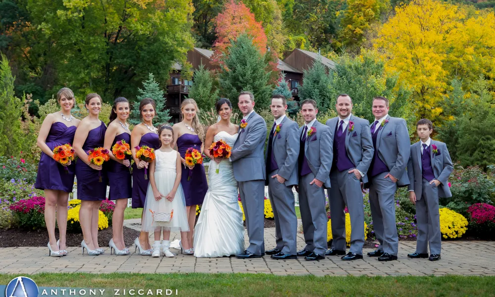 Wedding party featuring bride, groom, bridesmaids in purple short dresses and groomsmen in grey tuxes.