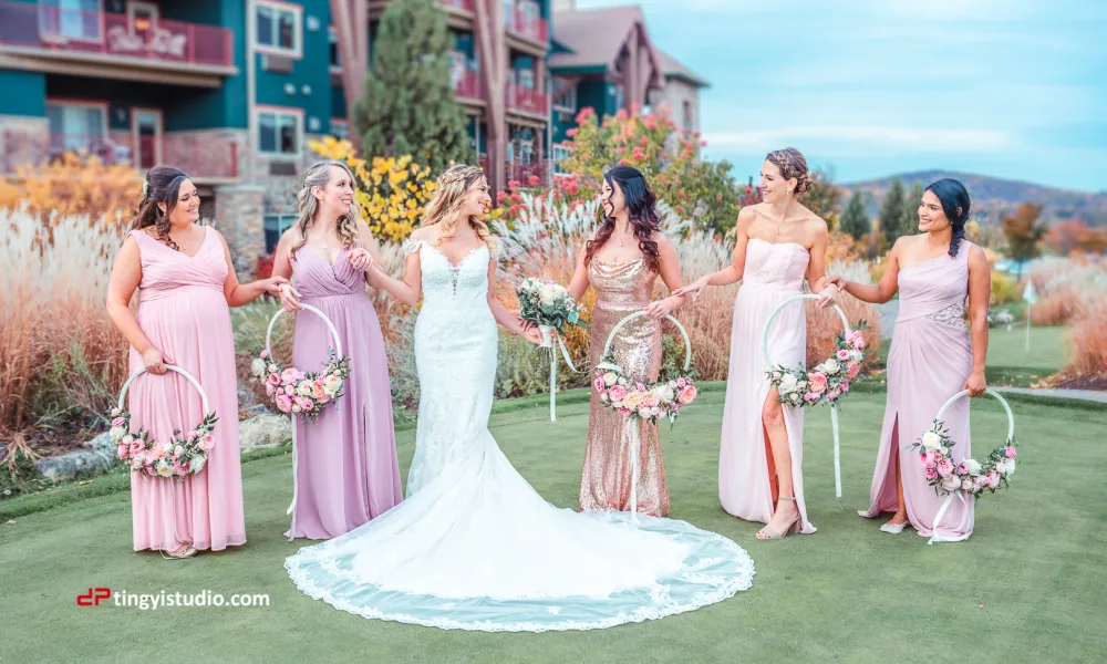 Bridesmaids wearing pink dresses stand hand in hand with the bride.