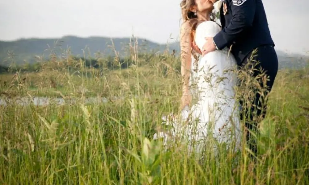 Man wearing his military uniform dips and kisses bride.