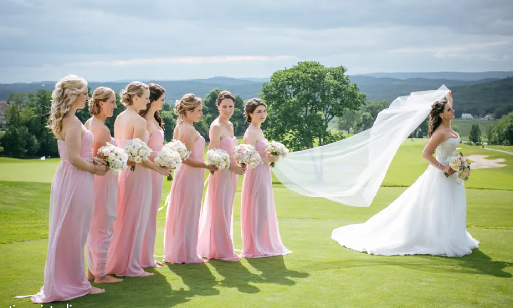 Bride stands bridesmaids who are wearing light pink dresses.