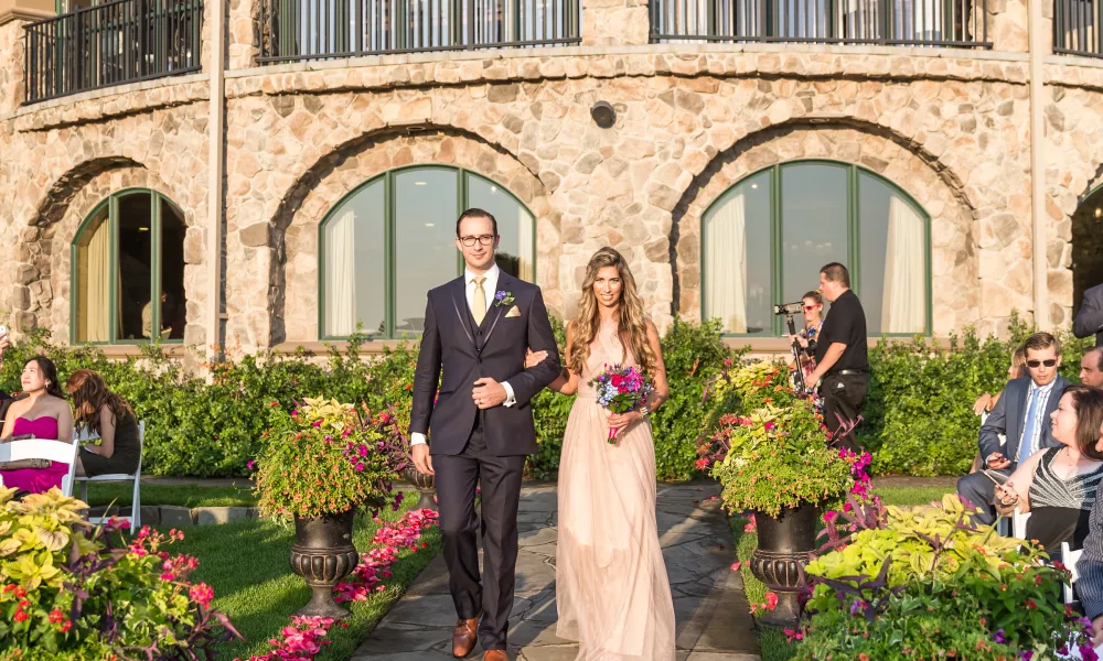 Bridesmaid and groomsmen walk arm in arm down path from Grand Cascades Lodge.