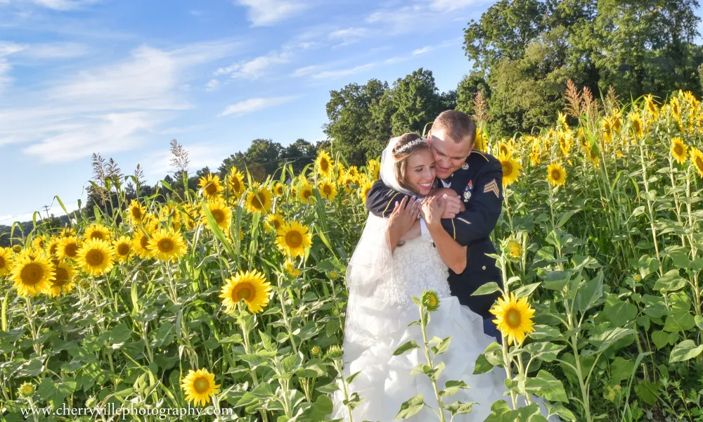 Bride and groom standing in field of sunflowers.