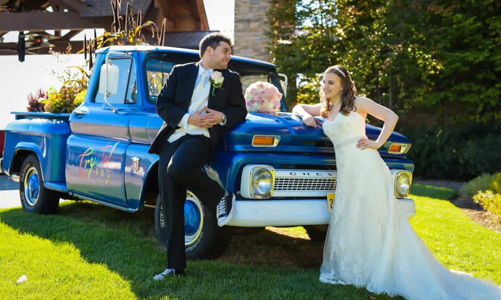 Bride and groom lean on Crystal Springs Resort blue truck