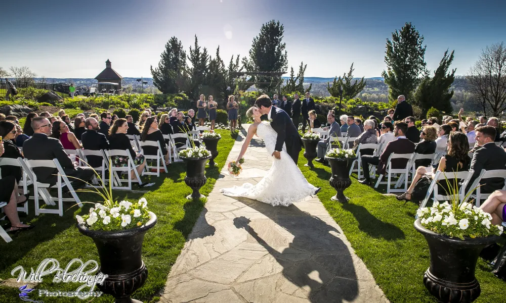 Groom dips bride and kisses her during wedding ceremony.