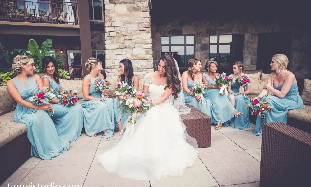 Bride and her bridesmaids, who are wearing light blue dresses, sit on Fire &amp; Water Terrace at Grand Cascades Lodge.