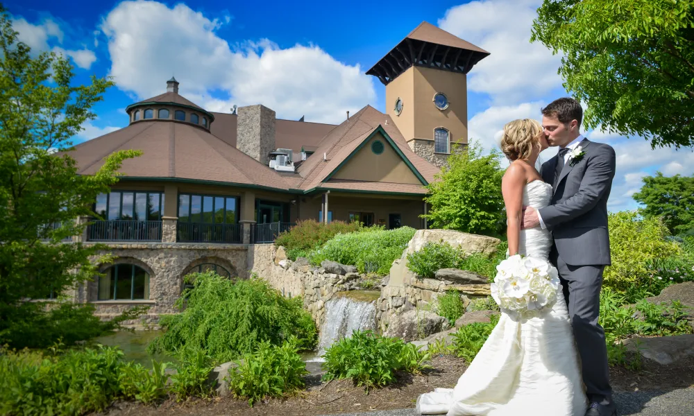 Bride and groom kissing in front of Crystal Springs Country Club