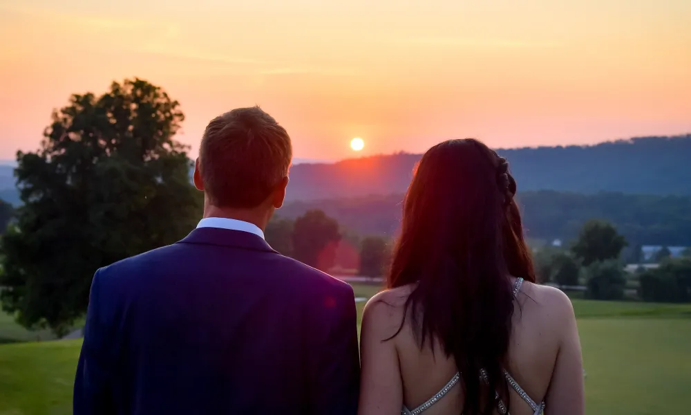 Bride and groom looking to the sunset on golf course