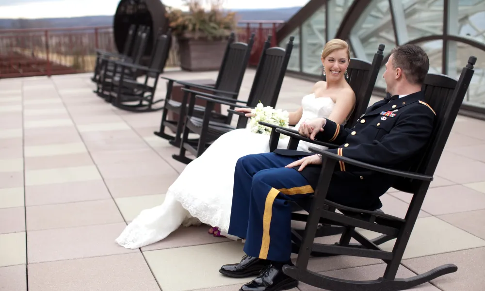 Military groom and bride sitting on rocking chairs on Fire &amp; Water Terrace