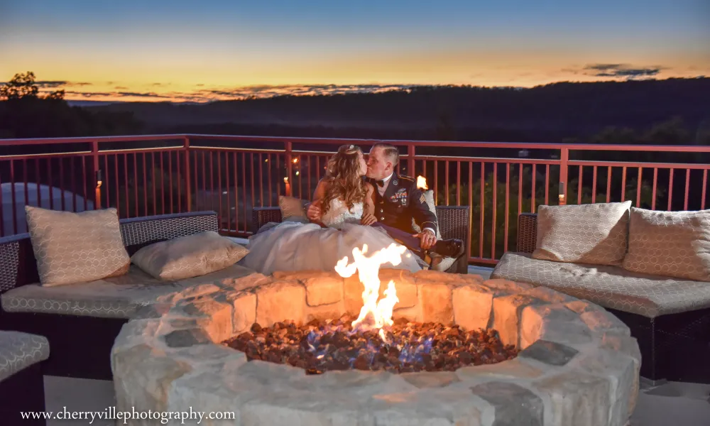 Bride and groom kissing over fire pit on Fire &amp; Water Terrace