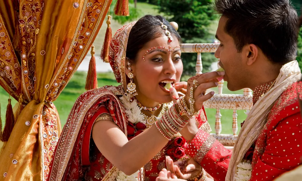 Indian bride and groom feeding each other