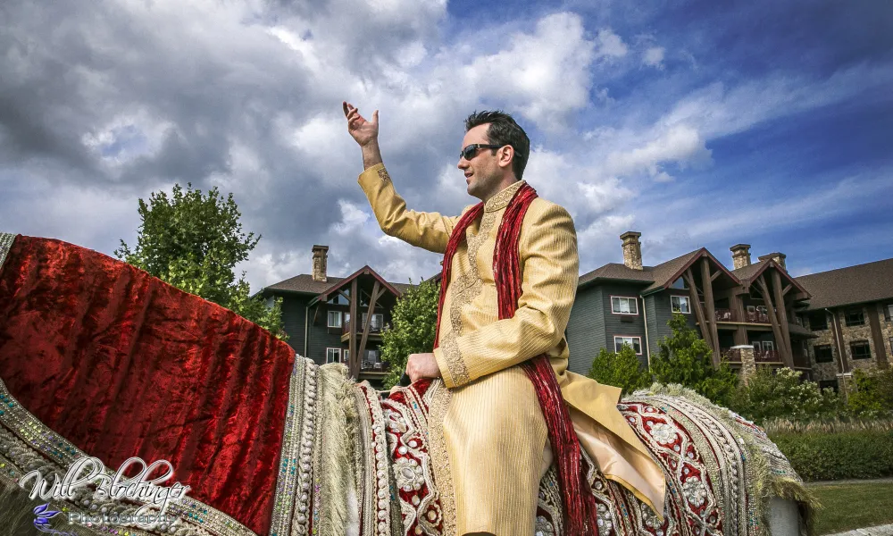 Indian groom riding white horse