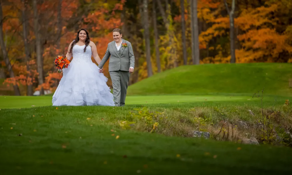 Brides holding hands walking Black Bear golf course