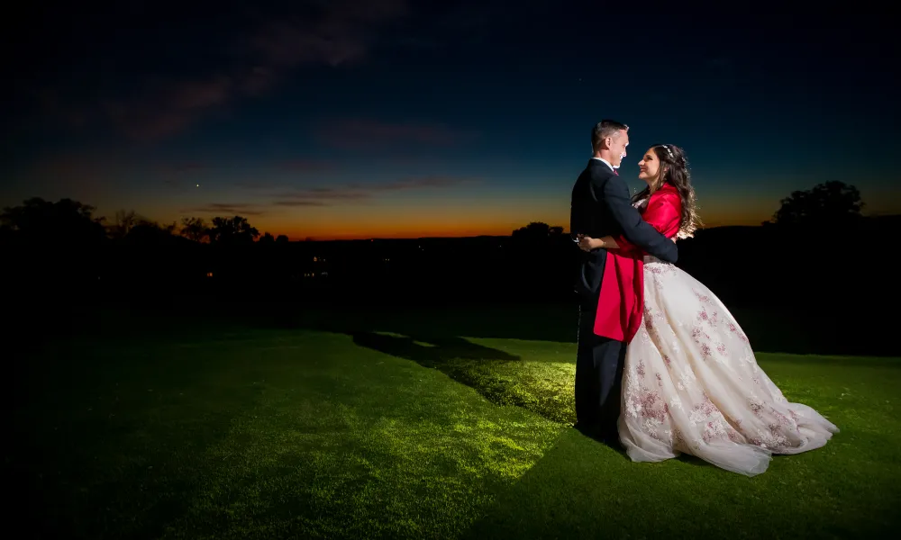 Bride and groom hug during sunset.