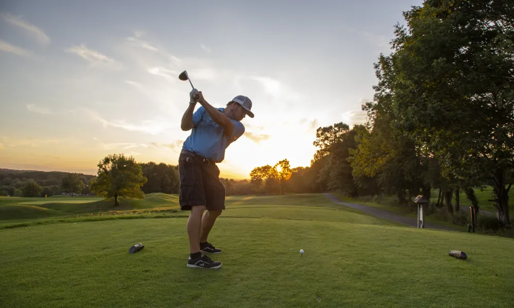 Man in blue shirt teeing off at Black Bear Golf Course