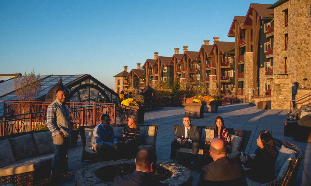 Group of people sitting by the fire pit on the terrace at Grand Cascades Lodge