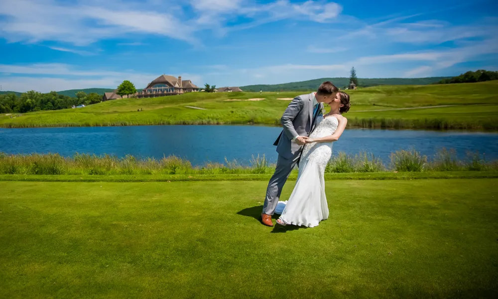 Bride and groom kissing in front of Ballyowen Golf Club