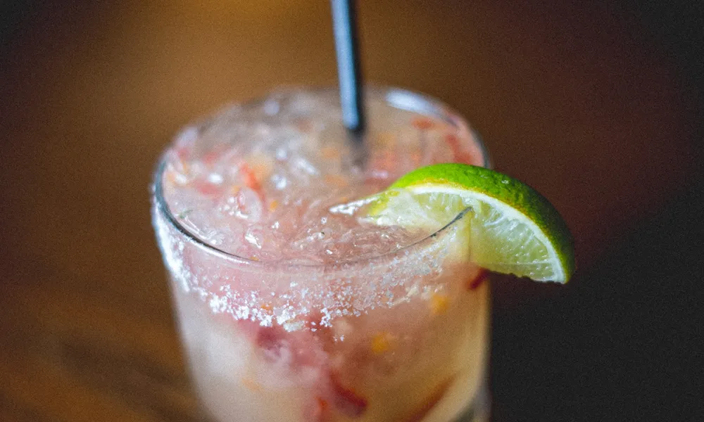 Cocktail in short round glass with lime wedge and salt.