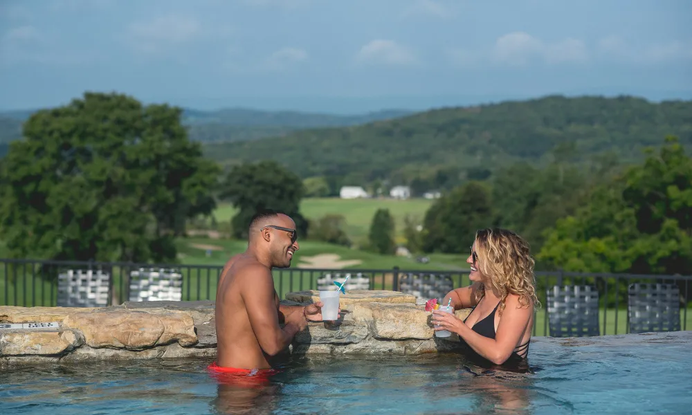 Couple sipping cocktails at the Vista 180 pool at Crystal Springs Resort