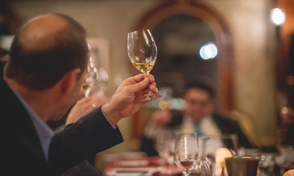 Man holding up glass filled with white wine.