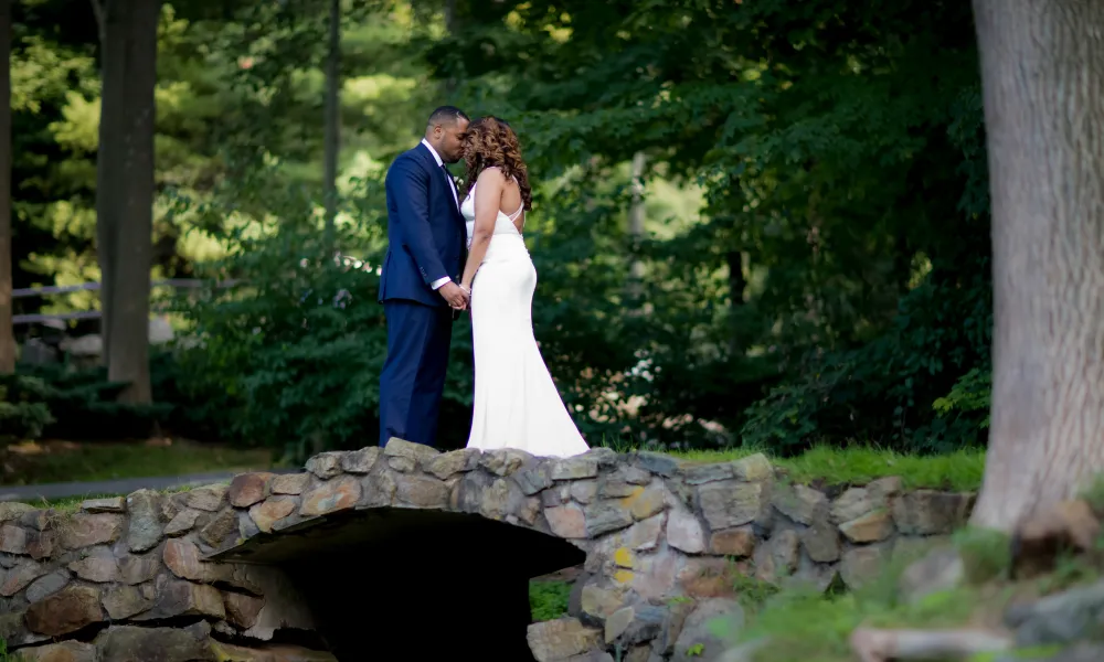 Bride and groom touching heads on bridge