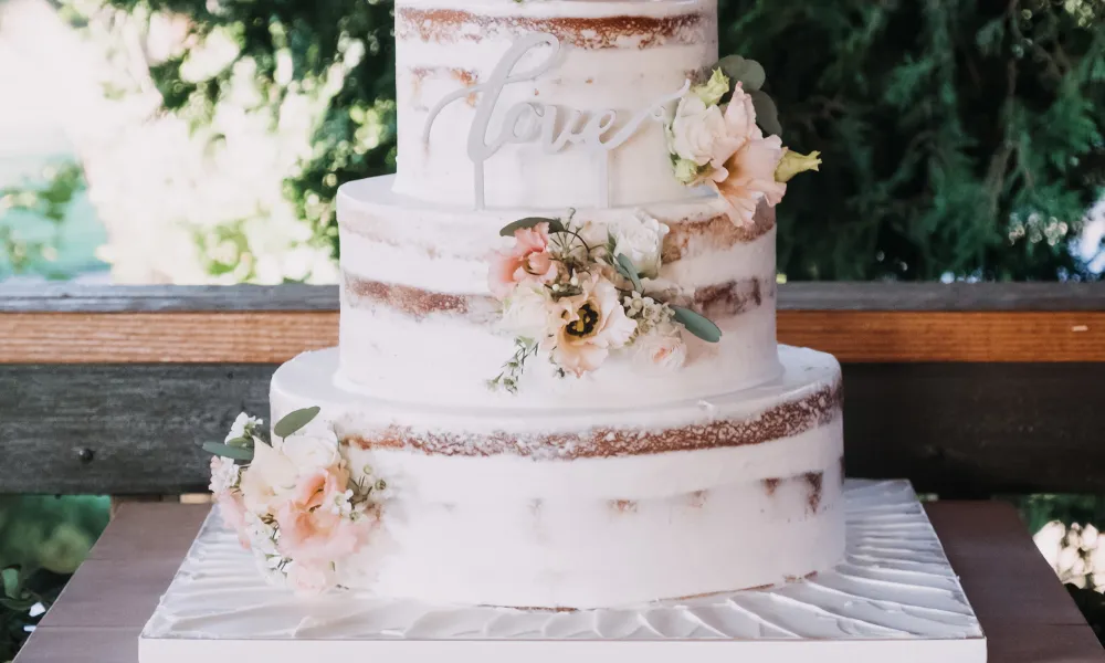 Wedding cake decorated with flowers and &quot;love&quot; sign