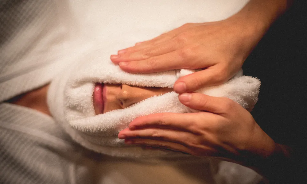 Warm towel around woman's face.