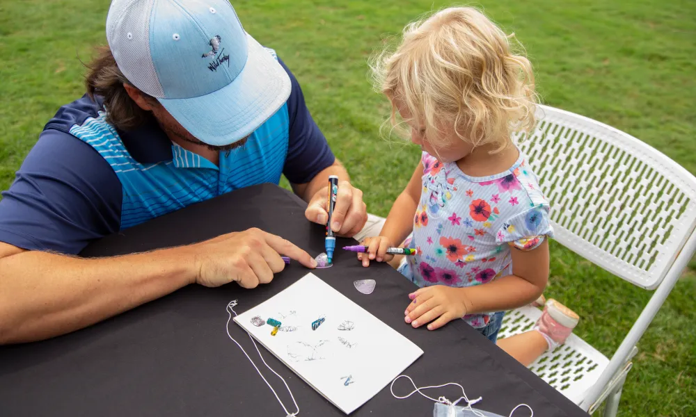 Adult helping child make shrinky jewelry